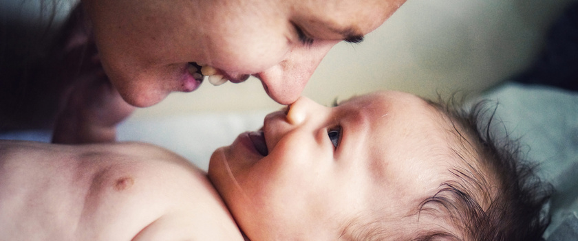 Humana Baby lächelt Mama an