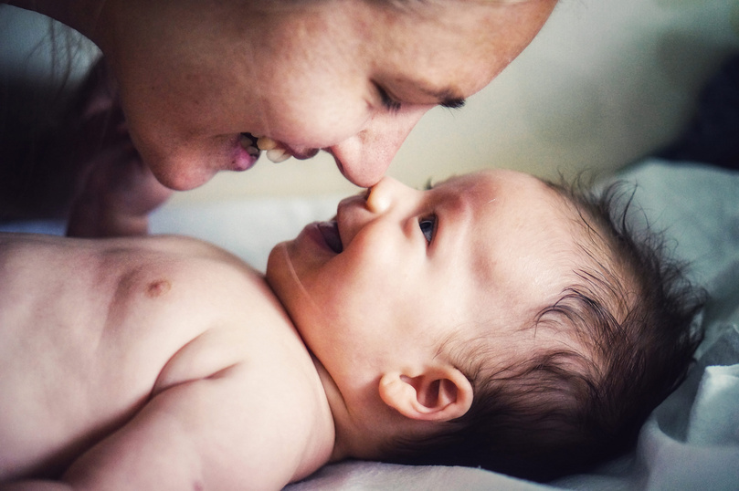 Humana Baby lächelt Mama an